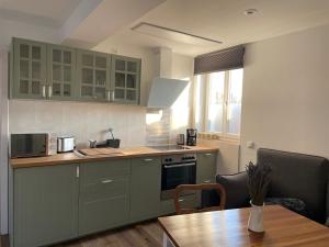 a kitchen with green cabinets and a wooden table at Zschampert Hof bei Leipzig Ruhige Ferienwohnung Landliebe für 2-3 Personen in Markranstädt