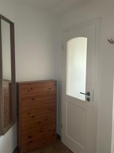 a bedroom with a door and a wooden dresser at Zschampert Hof bei Leipzig Ruhige Ferienwohnung Landliebe für 2-3 Personen in Markranstädt