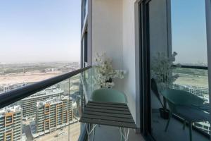 een balkon met een groene stoel en uitzicht op de stad bij Modern 1bdr - 10min from Burj Khalifa - Sobha Waves in Dubai