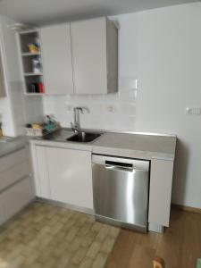 cocina con armarios blancos y fregadero de acero inoxidable en Apartment Jalen en Bohinjska Bela