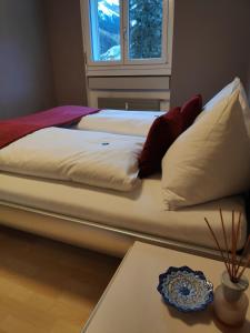 a bed with white pillows and a plate on a table at Central Serviced Apartment in Engelberg