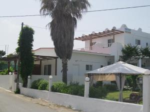 una casa bianca con una palma e un ombrello di Seaside Studios Kirania a Kiotari
