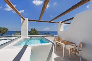 a villa with a swimming pool and a table and chairs at Nissia Beach Apartments & Suites in Kamari