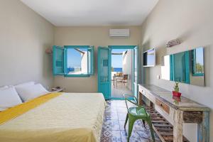 a bedroom with a bed and a desk and windows at Nissia Beach Apartments & Suites in Kamari