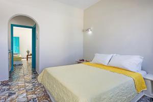 a bedroom with a bed with a yellow blanket on it at Nissia Beach Apartments & Suites in Kamari