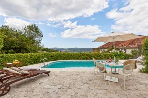 a pool with a table and chairs and an umbrella at Villa Ava in Kotor