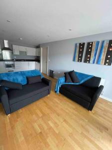 a living room with two black couches and a kitchen at 2 Bedroom Flat in Bedford
