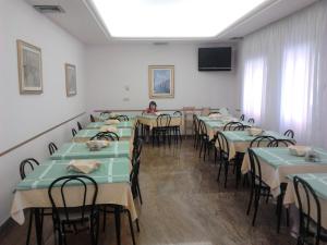 une chambre avec des tables et des chaises et une femme y assise dans l'établissement Hotel Nuova Doel, à Sottomarina