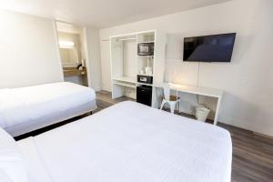 ein Hotelzimmer mit 2 Betten und einem Schreibtisch mit einem TV in der Unterkunft Oneway Savannah in Savannah