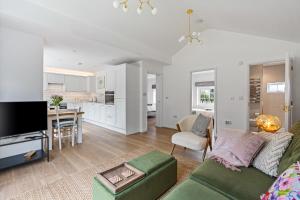 a living room with a green couch and a kitchen at Apple Tree Cottage in Welwyn