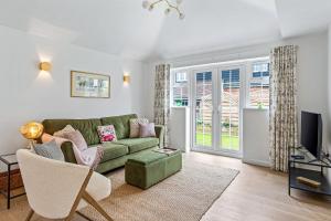 a living room with a green couch and a tv at Apple Tree Cottage in Welwyn