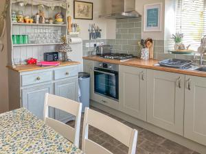 a kitchen with white cabinets and a table with chairs at Alma Cottage in Axminster