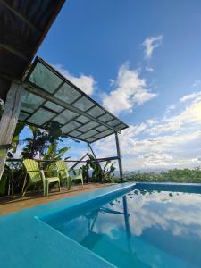 a swimming pool with two chairs and a pavilion at Finca La Puesta del Sol - Miramar de Sierpe in Sierpe
