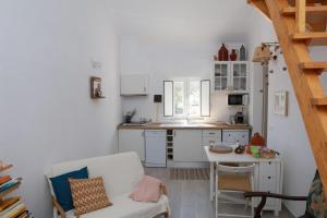 eine Küche mit weißen Schränken, einem weißen Stuhl und einem Tisch in der Unterkunft Típica Casa de Campo Alentejana in Montemor-o-Novo