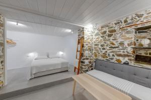 een slaapkamer met een bed en een stenen muur bij Artdecosyros Junior in Ano Syros