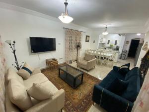 uma sala de estar com um sofá e cadeiras e uma televisão em فيلا برايفت بول في مارينا الساحل الشمالي em El Alamein