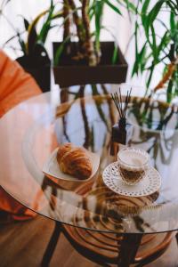 une table en verre avec un croissant et une tasse de café dans l'établissement Hotel DENINNA, à Vinnytsia