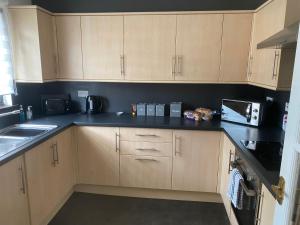 a kitchen with wooden cabinets and a black counter top at Argyll Apartment Loch Lomond in Balloch