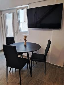 a dining room table with chairs and a television on a wall at Apartman Gallery Freya in Zadar