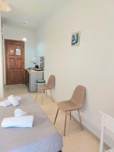 ein Zimmer mit einem Bett und zwei Stühlen und eine Küche in der Unterkunft Athina apartments in Argassi
