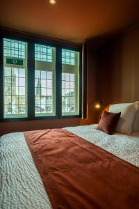 a bedroom with a large bed and windows at Guest House La Civière d'or in Bruges