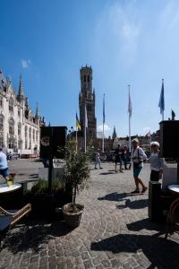 un grupo de personas caminando alrededor de una plaza con una torre del reloj en Guest House La Civière d'or, en Brujas