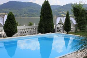 a blue swimming pool in front of trees and a lake at Vila Selina in Eşelniţa