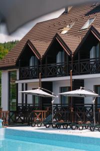 a building with two umbrellas next to a swimming pool at RUBEL APARTHOTEL&SPA in Yaremche