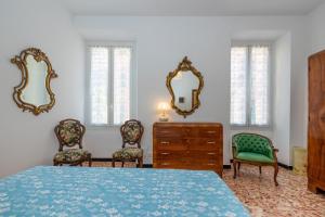 a bedroom with a bed and two chairs and mirrors at In the heart of Finalmarina in Finale Ligure
