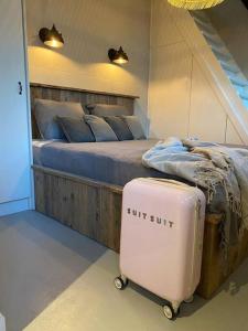 een slaapkamer met een bed met een koffer ernaast bij Stijlvol huisje met veranda! Tuynloodz A in Beers