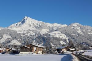 uma montanha coberta de neve com uma aldeia em primeiro plano em Apartment Alpine by Apartment Managers em Kirchberg in Tirol