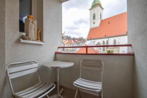 a balcony with two chairs and a table and a church at Apartment Old Centre - Panska in Bratislava