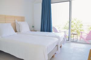 1 Schlafzimmer mit 2 weißen Betten und einem Balkon in der Unterkunft Le Toit Penché in Tardinghen