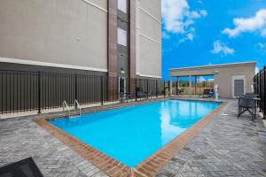 - une piscine d'eau bleue en face d'un bâtiment dans l'établissement La Quinta Inn & Suites by Wyndham Sulphur Lake Charles, à Sulphur