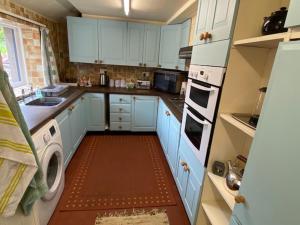 una pequeña cocina con armarios azules y lavadora en lake District cottage en Bootle