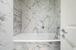 a white bathroom with a white tub and marble walls at The Hearth of Westminster in London