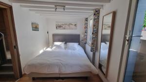 ein Schlafzimmer mit einem weißen Bett und einem Spiegel in der Unterkunft Maison du quai à Saint Valéry sur Somme in Saint-Valery-sur-Somme