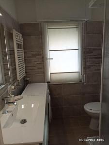 een badkamer met een wastafel, een toilet en een raam bij b&b Poseidone in Alassio