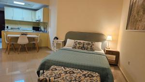 ein Schlafzimmer mit einem Bett und einem Tisch sowie eine Küche in der Unterkunft Luxury see view studio Al Marjan in Ras al Khaimah