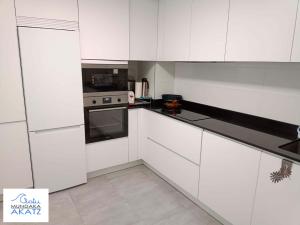 una cocina blanca con armarios y electrodomésticos blancos en APARTAMENTO AKATZ, en Mundaka