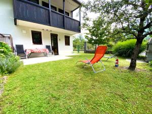 a red chair sitting in the yard of a house at Apartma EMI in Bovec