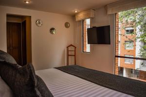 1 dormitorio con 1 cama, TV y ventana en Cora 96 Street Apartments, en Bogotá