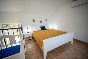 a bedroom with a white bed with a yellow blanket at Studio apartment Villa Radovic in Strp