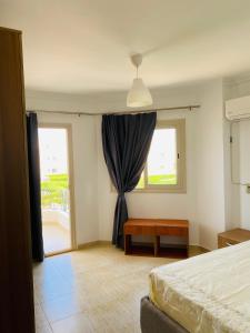 1 dormitorio con cama, ventana y mesa en شالية Golden Beach 1, en Raʼs Matarma