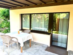 eine Terrasse mit einem Tisch, Stühlen und einem Fenster in der Unterkunft Apartment Deluxe with Garden Rapperswil-Jona in Jona