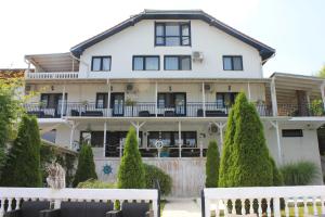 une grande maison blanche avec des arbres devant elle dans l'établissement Vila Selina, à Eşelniţa