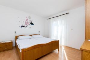 a bedroom with a wooden bed and a window at Apartments Biserka in Barbat na Rabu