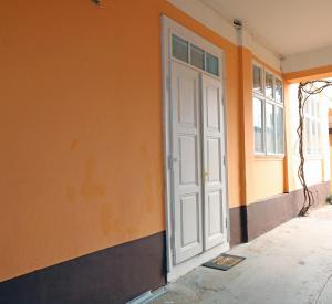 une porte blanche sur le côté d'un bâtiment orange dans l'établissement BIG APARTMAN BELA CRKVA, à Bela Crkva