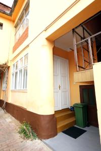 un bâtiment avec une porte blanche et une poubelle verte dans l'établissement BIG APARTMAN BELA CRKVA, à Bela Crkva