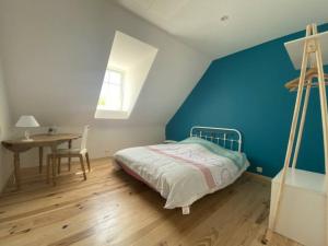 a bedroom with a bed and a desk and a blue wall at la grange in Offrethun